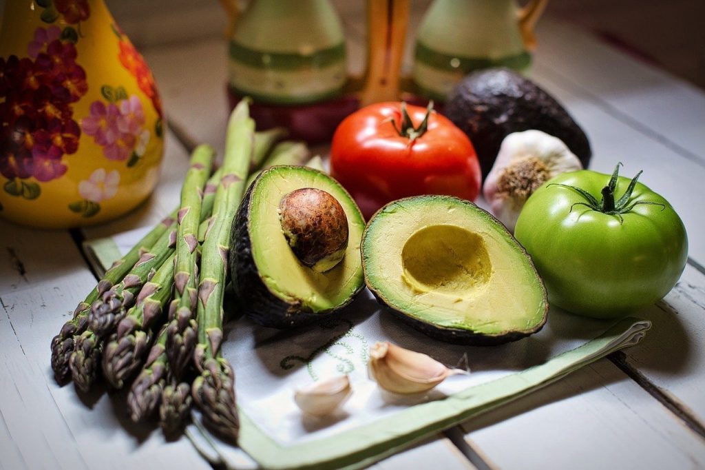 Avocado halves, asparagus, tomatoes, garlic, and avocado on table