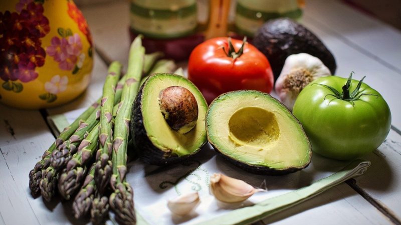 Avocado halves, asparagus, tomatoes, garlic, and avocado on table