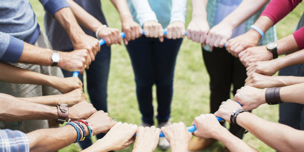 Team members hold a blue rope in a circle