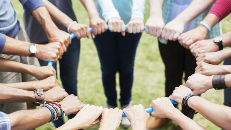 Team members hold a blue rope in a circle