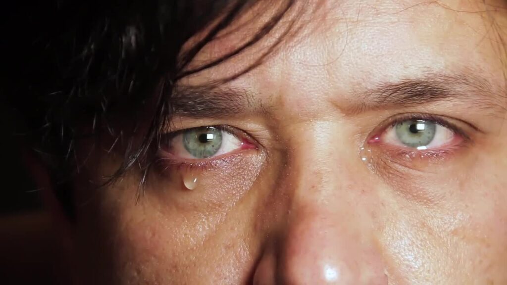 Close-up of tearful green eyes and a falling tear