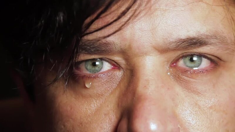 Close-up of tearful green eyes and a falling tear