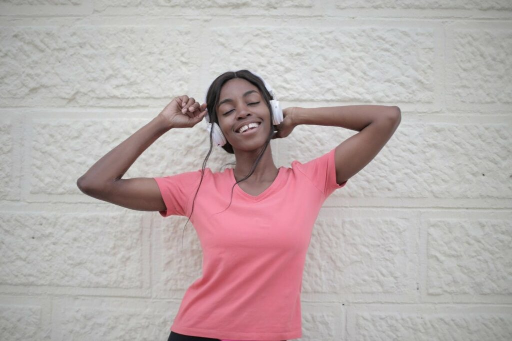Smiling woman in pink shirt listening to headphones