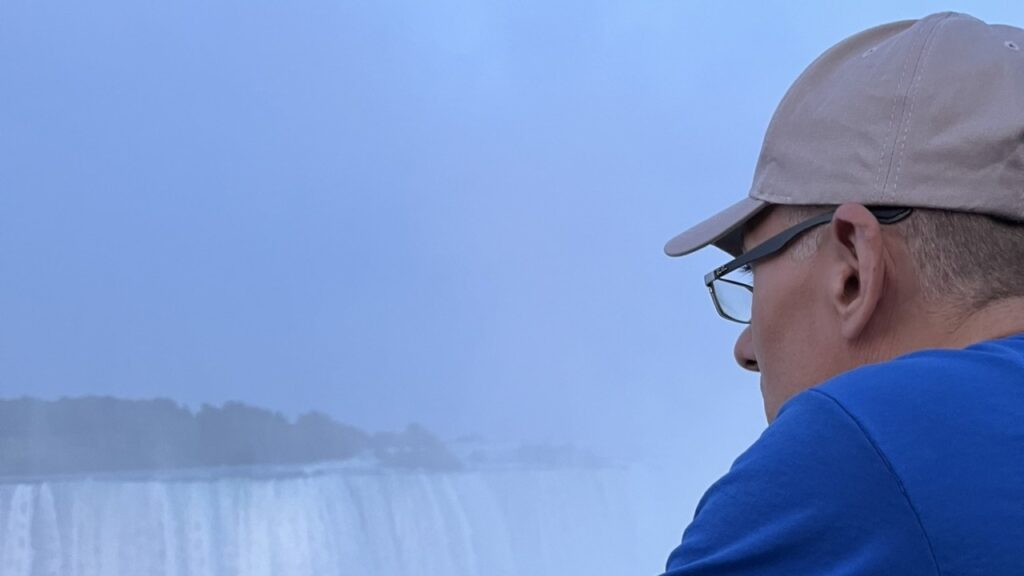 Man in cap views misty waterfall