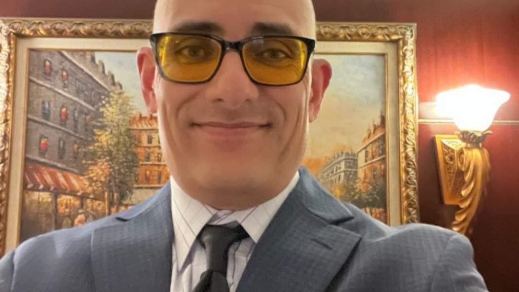 Smiling man in suit wearing yellow-tinted glasses